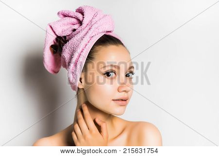 beautiful girl came out after showering with a pink towel on her head and cute looks at the camera, isolated on white background