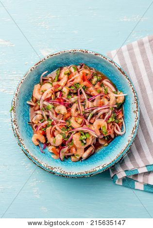 Ecuadorian shrimps ceviche sebiche with tomatoes in blue bowl, wooden blue background. Traditional ecuadorian colombian or mexican dish