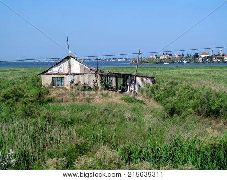 Single hut on the seashore among the reeds on a clear sunny day. Greenery blue sky sea bay shack and the city on the other shore on the horizon