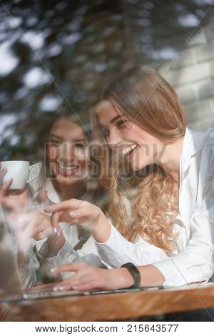 Vertical shot of two beautiful happy young women using laptp together at the local coffee shop friendship friends communication sisters bonding leisure togetherness emotions positivity internet.