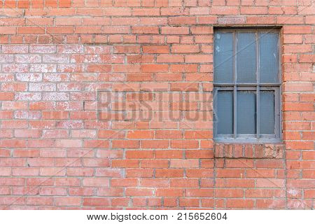 Old red brick textured wall with window on right side.