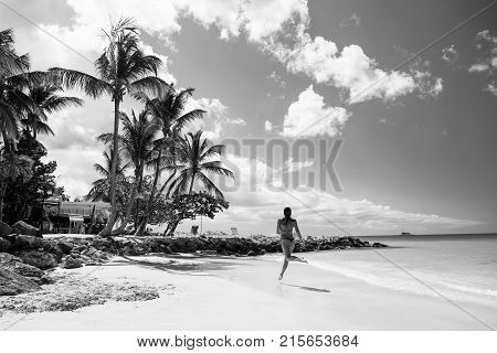 Young pretty woman with beautiful body in swimsuit running in ocean water sunny day at tropicl beach wellness concept