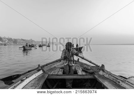 VARANASI INDIA - MARCH 15 2016: Black and white picture of indian oarsman at the boat at the sunrise in Ganges River in Varanasi India.