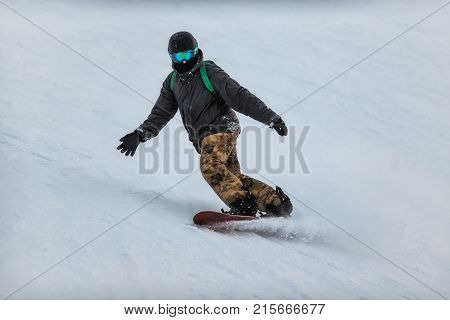 Snowboarder In A Black Helmet Riding On A Snowy Track.
