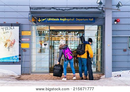 March 5 2017 - Rovaniemi Finland: Young couple with luggage bags at the entrance into Rovaniemi airport in winter
