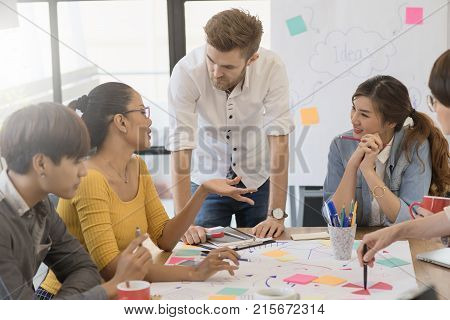 Multiethnic group of happy business people working together meeting and brainstorming in office using computer laptop tablet and mobile phone.