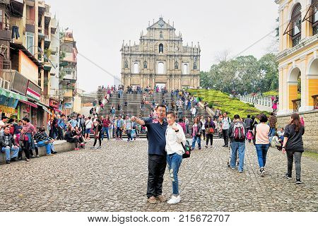 Macao China - March 8 2016: Couple making selfie photos at Ruins of Saint Paul Church in Historical old city center in Macao China. People on the background