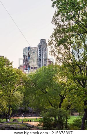 New York USA - May 6 2015: Park life with people relaxing and Midtown Manhattan skyline viewed from Central Park South in New York NYC USA. People in the distance.