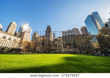 Green Lawn and Skyscrapers viewed from Bryant Park in Midtown Manhattan New York NYC USA. Tourists relaxing in the park