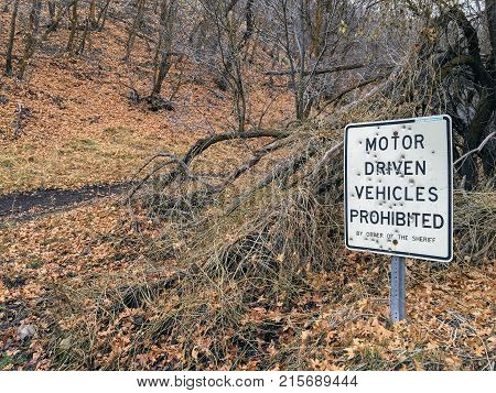 Motor Driven Vehicles Prohibited by order of the Sheriff sign with bullet holes, in forest trail on the Yellow Fork and Rose Canyon Trails in Oquirrh Mountains on the Wasatch Front in Salt Lake County Utah USA.