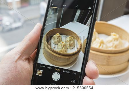 Shanghai, China - Nov 7, 2017: Taking photo of Shanghai dumpling, also called xiaolongbao with a smartphone. Xiaolongbao is a type of popular traditional food in China.