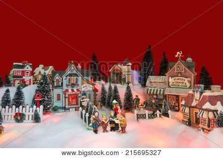 kid gospel choir singing and reads bible in the middle of Christmas village. Winter fairytale miniature scenery