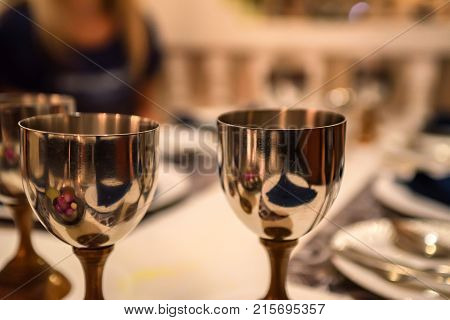 Close up image of several metal wine glasses on table in restaurant with blurred background