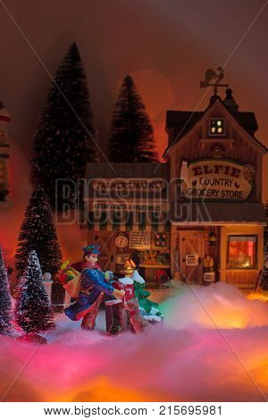 postman delivers holiday message with the backdropl is a snow Christmas town with elfie grocery store facade