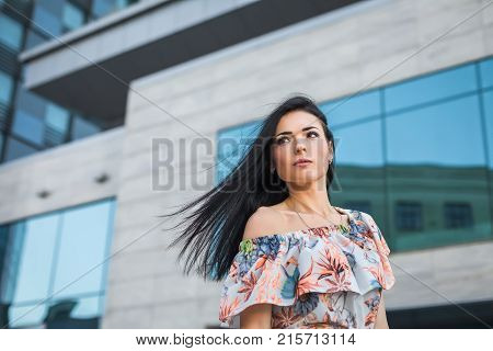 portrait of young thoughtfull female in the city, looking left. concept of freedom purposeful teenager, dressed in a summer dress with flower pattern