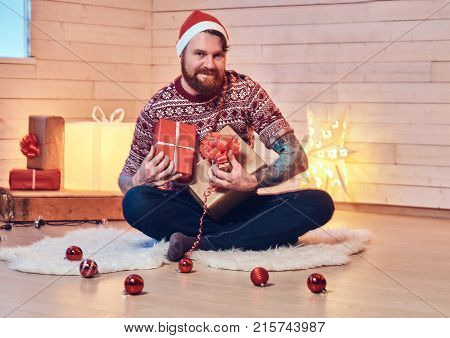 Redhead bearded male in Santa hat in a room with Christmas decoration.