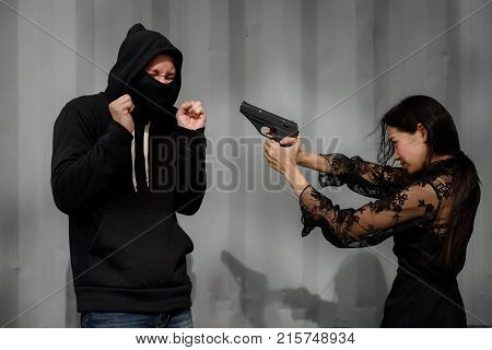 Scared Asian criminal robber Man raise hands to surrender and be arrested after plainclothes female police aim and point the gun to him.