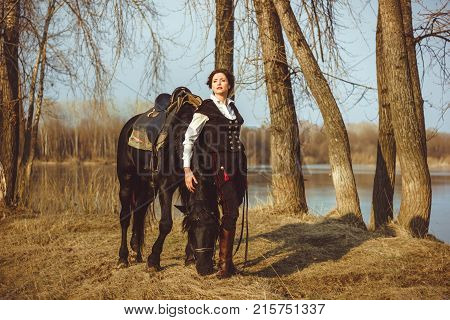 Portrait riding concept of advertising equestrian club caring for a horse. Jockey girl next to the horse. Corrects the bridle. Summer. Toning.