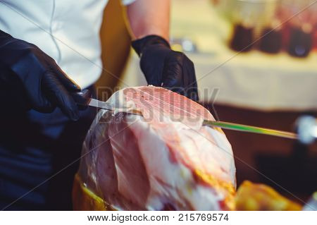 Sliced Dried Chamon Prosciutto. A Man Cuts A Jamon, A Warm Toned Image. Selective Focus Point