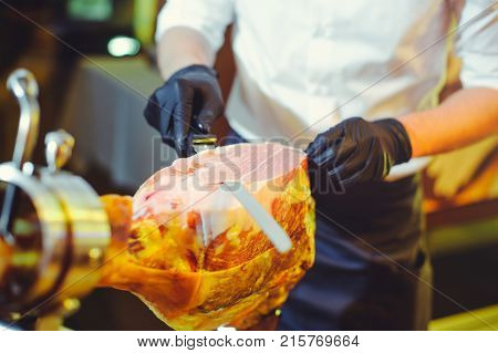 Sliced Dried Chamon Prosciutto. A Man Cuts A Jamon, A Warm Toned Image. Selective Focus Point