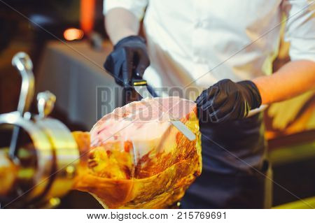 Sliced Dried Chamon Prosciutto. A Man Cuts A Jamon, A Warm Toned Image. Selective Focus Point