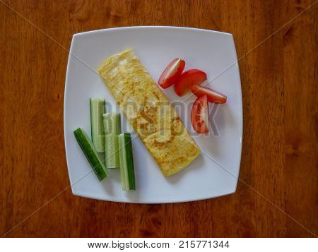 Classic omelet with tomatoes and cucumbers on the white plate. Fresh breakfast.