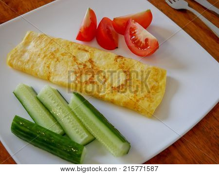 Classic omelet with tomatoes and cucumbers on the white plate. Fresh breakfast.
