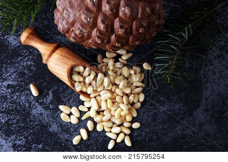spoon with pine nuts with pinoli pine cones in the background.