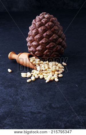 spoon with pine nuts with pinoli pine cones in the background.