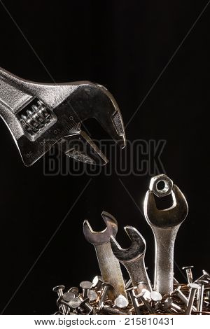 Conception of an adjustable wrench feeding baby wrenches in a nest of nails