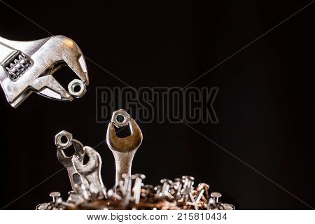 Conception of an adjustable wrench feeding baby wrenches in a nest of nails