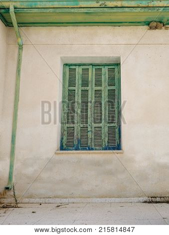 Old Cyprian window with green shutter and drainpipe.