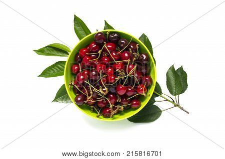 Fresh red cherry with green leaves on green plate isolated on white. Top view