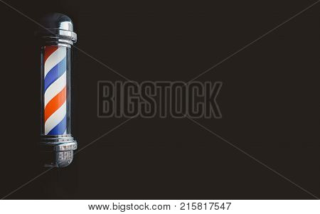 Barber shop pole baner at entrance of the window. background is dark. copyspace