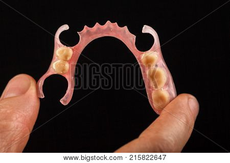 Dental prosthesis in the hand of the dentist. Close-up on a black background