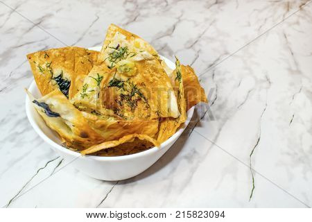 Homemade Chips. Flour tortilla chips in a ceramic bowl. Useful healthy snacks from a thin dough. Fried lavash with seasonings and greens