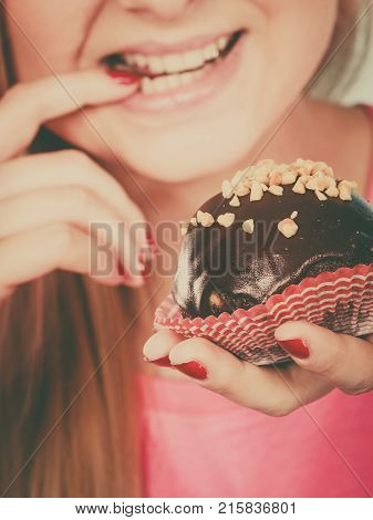 Diet sweets food concept. Woman holding delicious chocolate cupcake with peanut frosting about to take bite