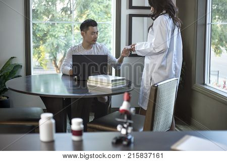 Female scientist in a lab coat researching with her male coed med school student in a campus laboratory. The woman is learning science and technology in medical industry.