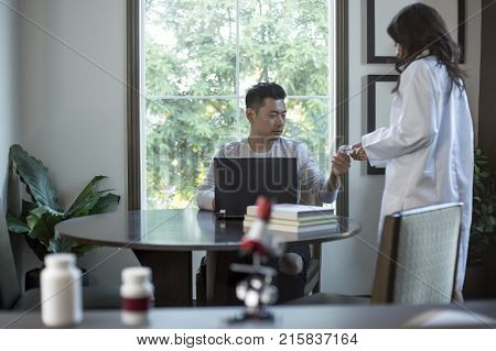 Female scientist in a lab coat researching with her male coed med school student in a campus laboratory. The woman is learning science and technology in medical industry.