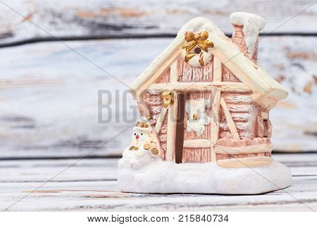 Gingerbred house in snow on wooden background. Gingebread house with snowman. Handmade gift for Christmas and New Year.