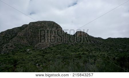 Photo of rocky mountain with a green vegetation in desert area. 