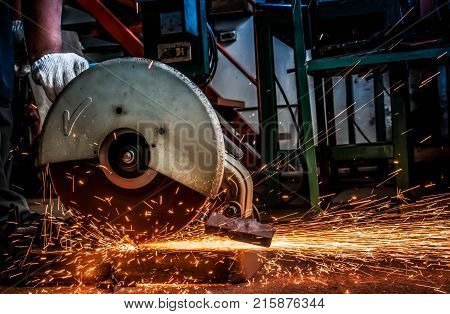 Hand of worker man using machine electricity tool cutting steel and sparks while cutting iron. background
