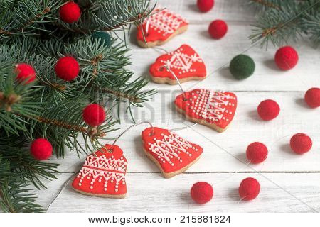 Gingerbread bells, a garland of faded beads and spruce branches on a light background - a Christmas or New Year's card. Selective focus.