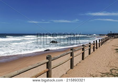 Wooden Pole Barrier On Beachfront Against Coastal  Landscape