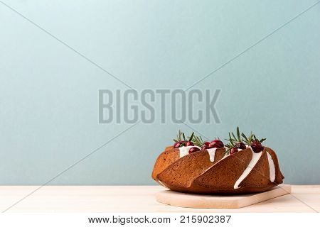 Shaped cake topped with icing and garnished with natural decor served on blue background fo Christmas.