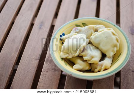 Close up plate full of delicious slavic dumplings vareniki on wooden surface