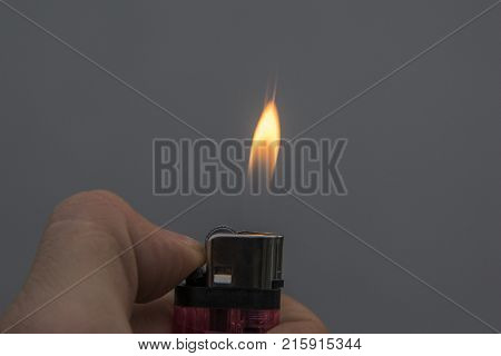 male hand holding a plastic gasoline lighter with lighter flame