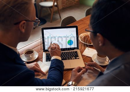 Coworkers discussing business diagram on laptop screeen