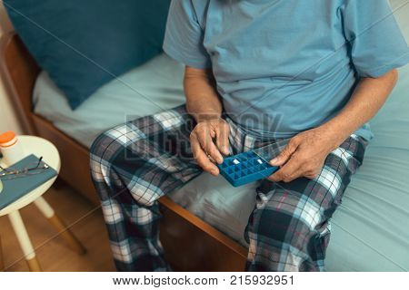 Senior Man Sitting On Bed At Home Taking Medication close up