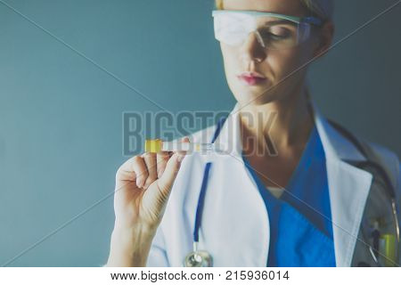 Female medical or research scientist or doctor using looking at a test tube of clear solution in a lab or laboratory